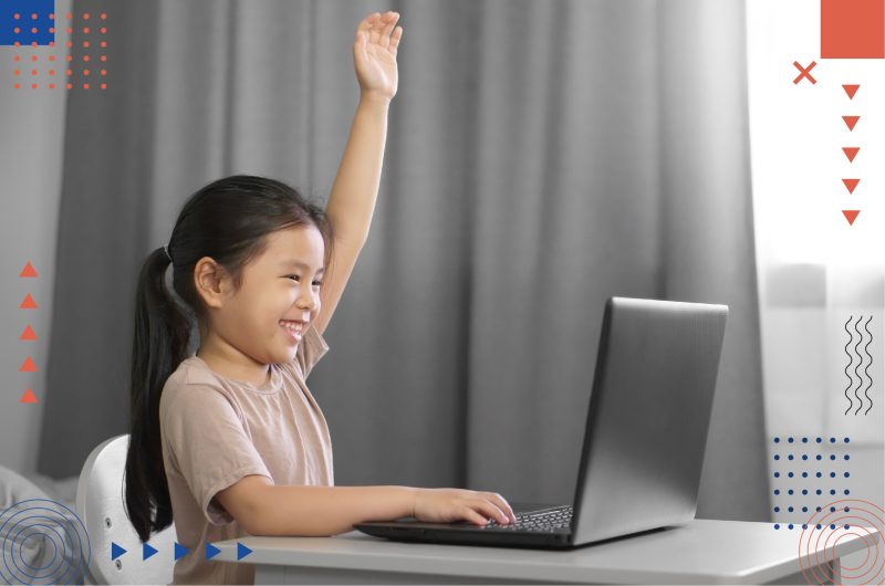 A happy student attending an online school session and raising her hands showing her participation.