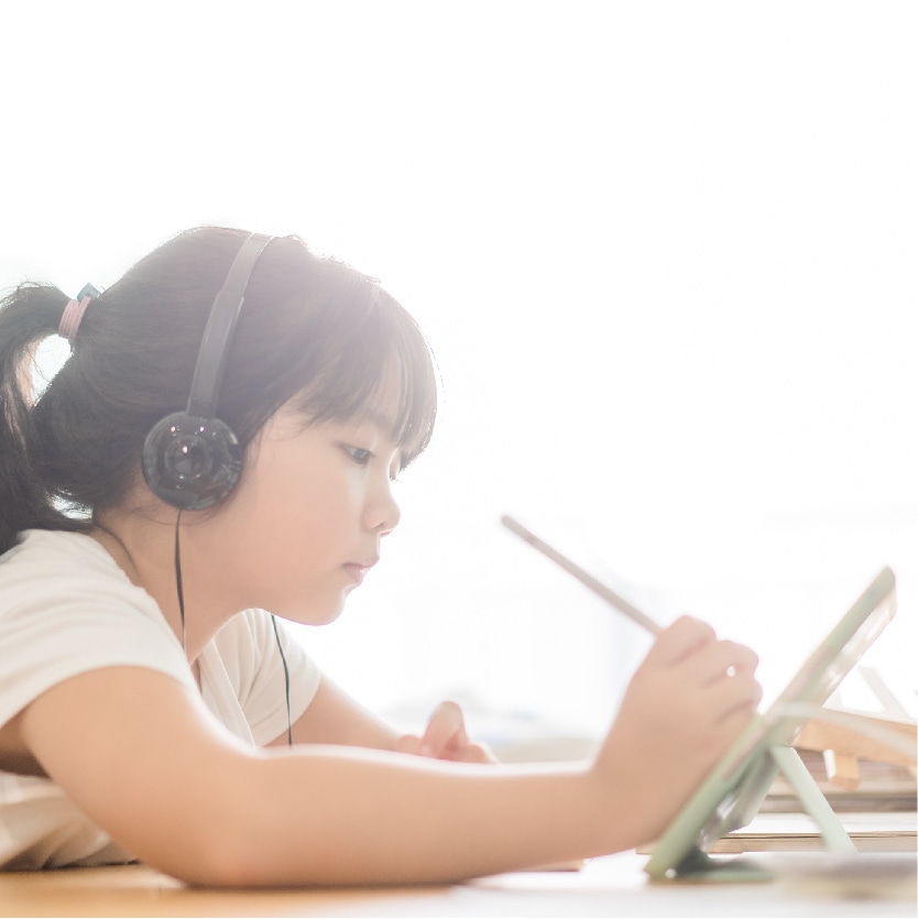 A young girl with a learning device and headset attending a PSLE session.
