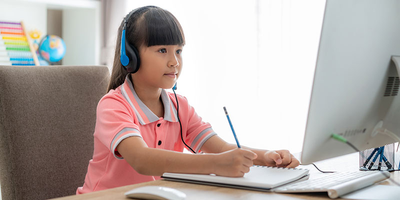 A girl student practising stimulus-based oral communication for her PSLE exam on her personal computer.