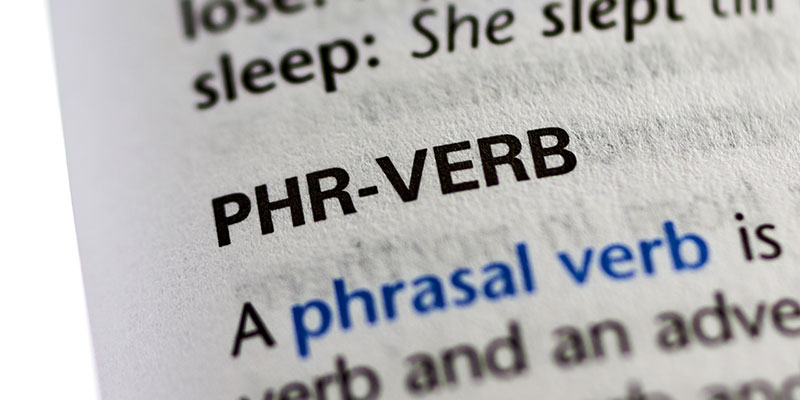 A page in the dictionary shows a close view for the text Phrasal verb along with its meaning. The text Phrasal verb is highlighted in blue.