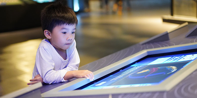 A small kid is learning a PSLE science lesson with an interactive touch screen.