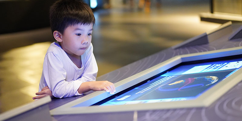 A boy kid touching and learning from the interactive screen
