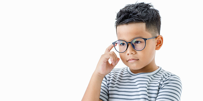 The role of critical thinking in PSLE maths success is illustrated by an Asian boy wearing glasses and thinking seriously.